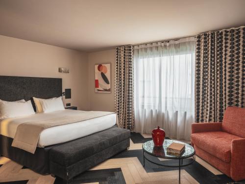 une chambre d'hôtel avec un lit et une chaise rouge dans l'établissement Le Rayz Vendome, à Paris