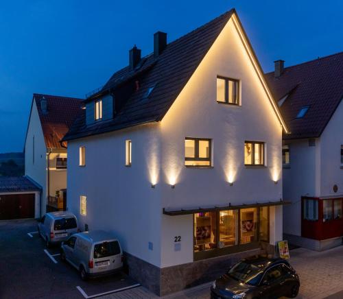 une maison blanche avec deux voitures garées dans un parking dans l'établissement Appartement Champagne, à Neuenstadt am Kocher