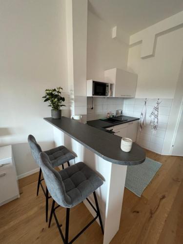 cocina con encimera negra y 2 sillas en Pannonia Appartements, en Bad Tatzmannsdorf