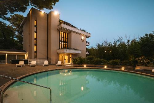 a large swimming pool in front of a house at Hotel De La Ville in Riccione