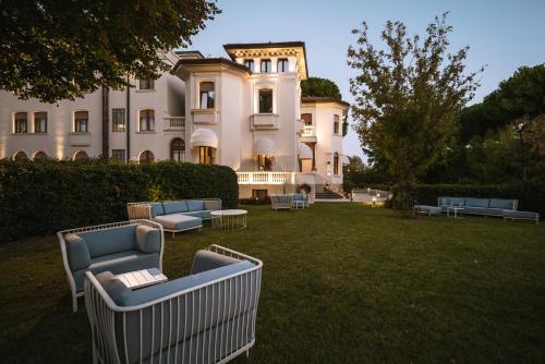 a large white building with chairs in the yard at Hotel De La Ville in Riccione