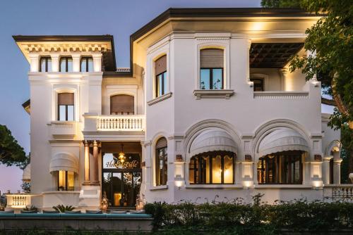 a large white house with its lights on at Hotel De La Ville in Riccione