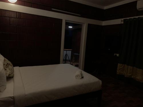 a bedroom with a white bed in a dark room at Casilda By The Oaks Inn in Ernakulam