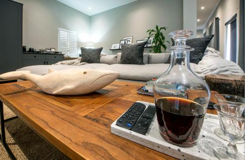 a table with a bottle of wine and a remote control at The Oyster Box Beach House by The Oyster Collection in Kenton on Sea