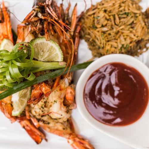 a plate of food with seafood and a bowl of sauce at Victoria Crown Plaza Hotel in Lagos