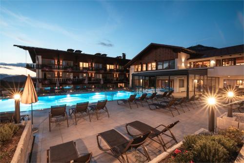 a hotel patio with chairs and a swimming pool at night at Hotel Sperlhof in Windischgarsten