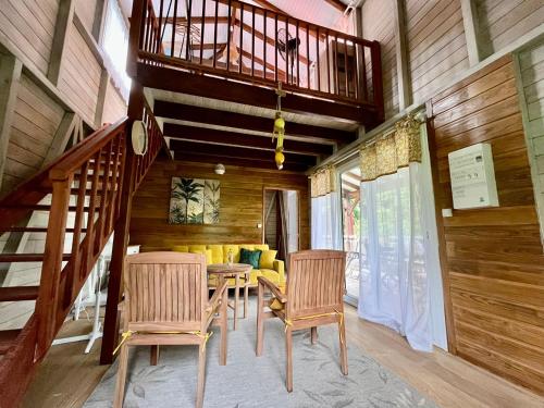 ein Esszimmer mit einem Tisch und Stühlen sowie einem Balkon in der Unterkunft Mahogany Lodge - Oasis cosy in Rivière-Pilote