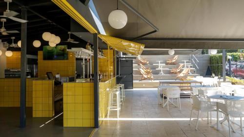 プラヤ・デ・パルマにあるCabot Tres Torres Apartamentosの黄色のタイルを用いた白い椅子とテーブルのあるレストラン