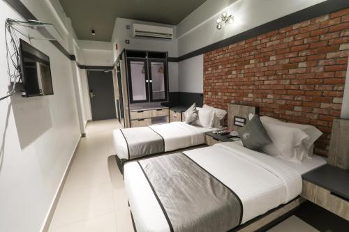 a bedroom with two beds and a brick wall at Vits Select Kudro Destinn in Mangalore