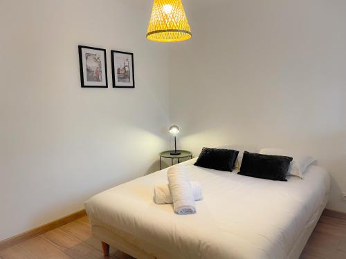 une chambre avec un grand lit blanc avec une lampe dans l'établissement Appartement 2 chambres Le Descartes, à Calais