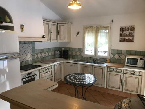 - une cuisine avec des placards blancs, un évier et une table dans l'établissement Villa Ste lucie de porto vecchio, à Sainte-Lucie de Porto-Vecchio