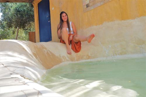 a woman sitting on a slide next to a swimming pool at Carmey Avdat Farm in Midreshet Ben Gurion