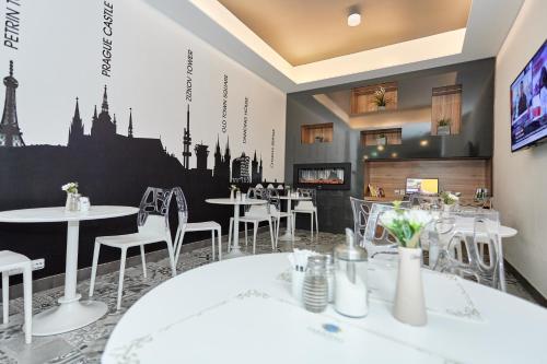 a restaurant with white tables and chairs and a tv at Hotel Garden Court in Prague