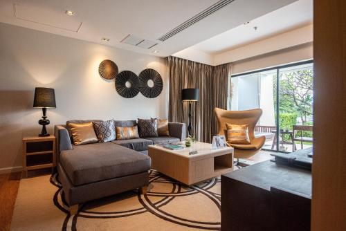 a living room with a couch and a table at Summit Windmill Golf Suite Hotel at Suvarnabhumi in Bangna