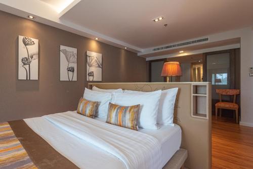 a bedroom with a bed with white sheets and pillows at Summit Windmill Golf Suite Hotel at Suvarnabhumi in Bangna