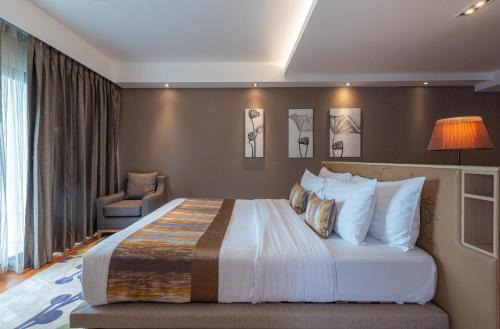 a hotel room with a large bed and a chair at Summit Windmill Golf Suite Hotel at Suvarnabhumi in Bangna