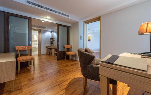 a living room with a table and chairs and a desk at Summit Windmill Golf Suite Hotel at Suvarnabhumi in Bangna