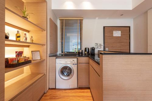 a laundry room with a washer and dryer at Summit Windmill Golf Suite Hotel at Suvarnabhumi in Bangna