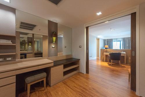 a bathroom with a vanity and a dining room at Summit Windmill Golf Suite Hotel at Suvarnabhumi in Bangna