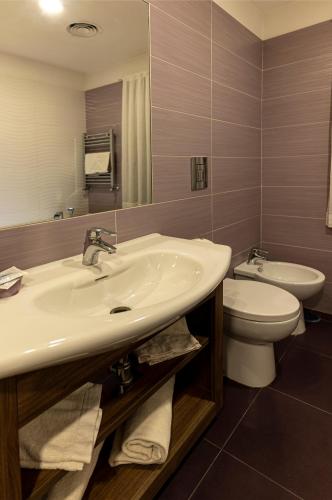a bathroom with a sink and a toilet and a mirror at Hotel Smeraldo in Qualiano
