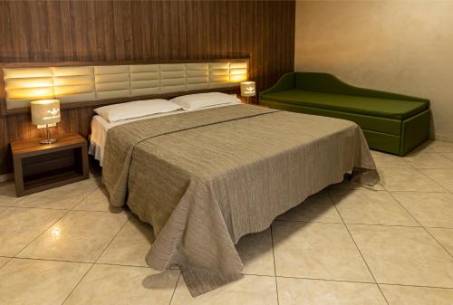 a bedroom with a bed and a green chair at Hotel Smeraldo in Qualiano