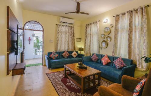 een woonkamer met een blauwe bank en een tafel bij GR Stays WHITE HOUSE 4bhk Private Pool Villa in Calangute in Calangute