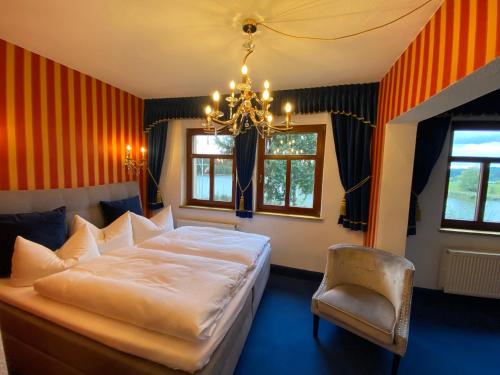 a bedroom with a bed and a chandelier and a chair at Riverdam in Ilmenau