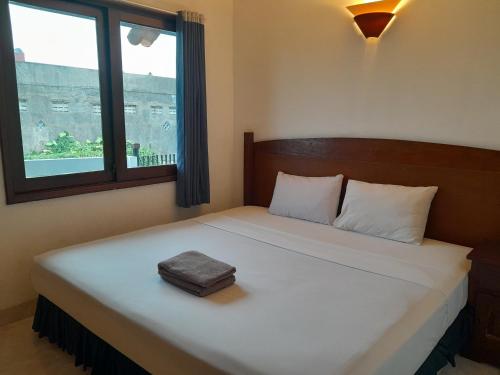 um quarto com uma grande cama branca e uma janela em The Green Winotosastro Hotel Yogyakarta em Yogyakarta