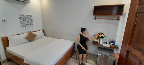 a woman standing in a small room with a bed at Sông Suối Homestay in Quy Nhon