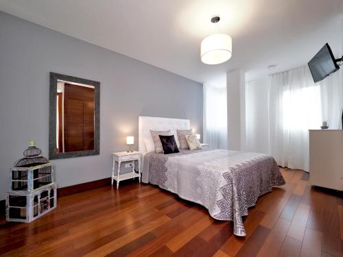 1 dormitorio con cama blanca y suelo de madera en Apartamento Monte Perdido, en Boltaña
