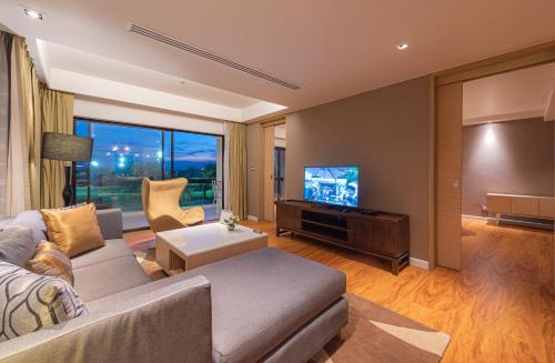 a living room with a couch and a flat screen tv at Summit Windmill Golf Suite Hotel at Suvarnabhumi in Bangna