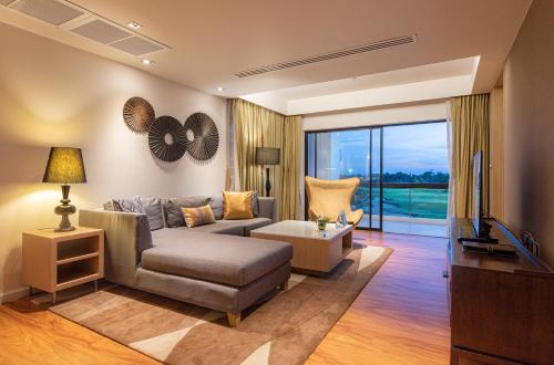 a living room with a couch and a tv at Summit Windmill Golf Suite Hotel at Suvarnabhumi in Bangna