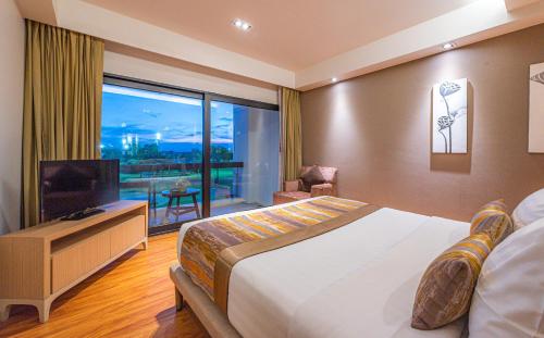 a hotel room with a bed and a large window at Summit Windmill Golf Suite Hotel at Suvarnabhumi in Bangna