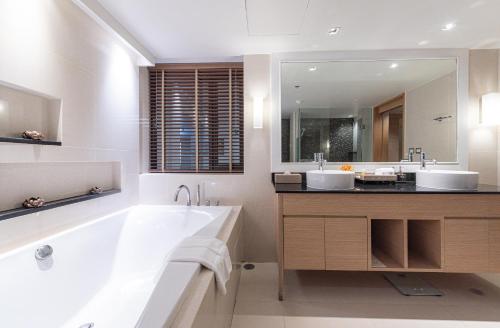 a bathroom with two sinks and a tub and a mirror at Summit Windmill Golf Suite Hotel at Suvarnabhumi in Bangna