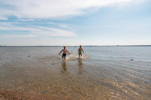 two men walking in the water on the beach at EuroParcs Poort van Zeeland in Hellevoetsluis
