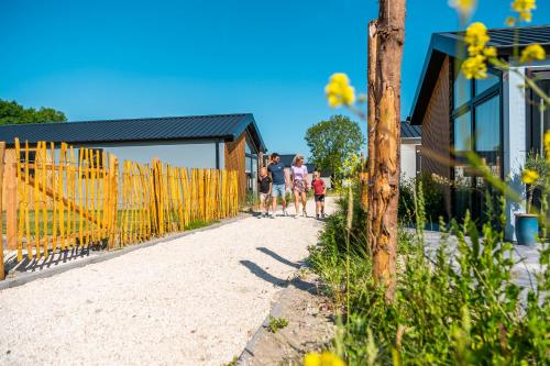 a group of people walking down a path next to a fence at EuroParcs Poort van Zeeland in Hellevoetsluis