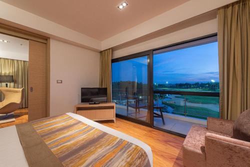 a bedroom with a bed and a large glass window at Summit Windmill Golf Suite Hotel at Suvarnabhumi in Bangna