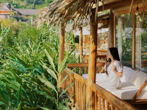a woman sitting on a porch of a house at Toce House Tả van in Sa Pa