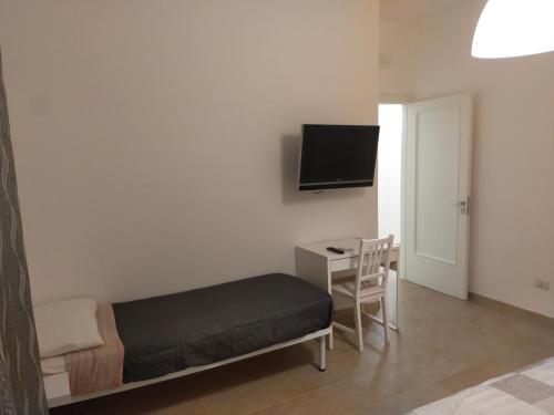 Cette chambre comprend un lit, un bureau et une télévision. dans l'établissement B&C rentals and events, à Lecce
