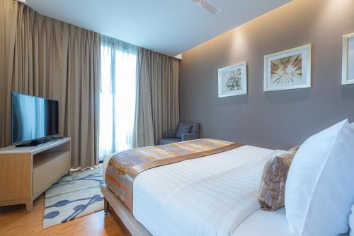 a hotel room with a bed and a flat screen tv at Summit Windmill Golf Suite Hotel at Suvarnabhumi in Bangna