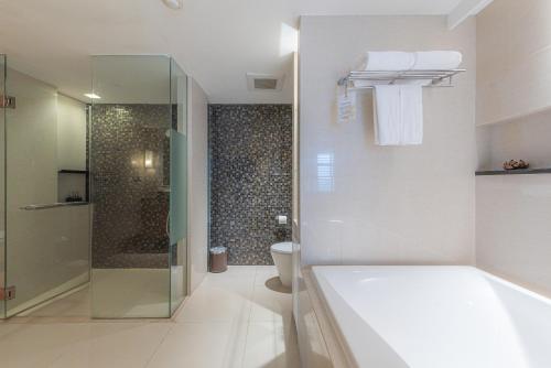 a bathroom with a tub and a shower and a toilet at Summit Windmill Golf Suite Hotel at Suvarnabhumi in Bangna