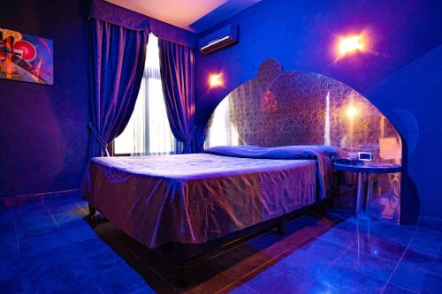 1 dormitorio con 1 cama en una habitación púrpura en Marcantonio Hotel, en Giugliano in Campania