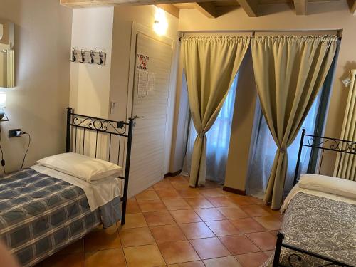 a bedroom with two beds and a door with curtains at La Casina in Dello