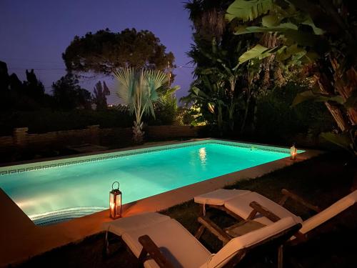een zwembad met 2 ligstoelen en een verlichte bij Las Gitanillas, villa with heated pool, La Cala de Mijas in Mijas Costa