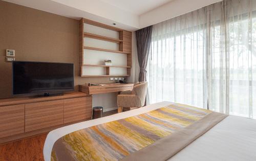 a hotel room with a bed and a flat screen tv at Summit Windmill Golf Suite Hotel at Suvarnabhumi in Bangna