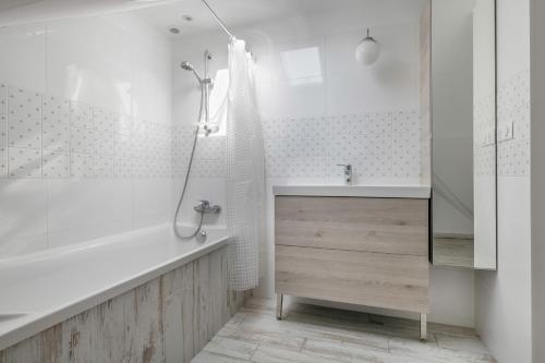 a white bathroom with a tub and a sink at Charmante maison à 250 mètres de la plage in Le Pouliguen