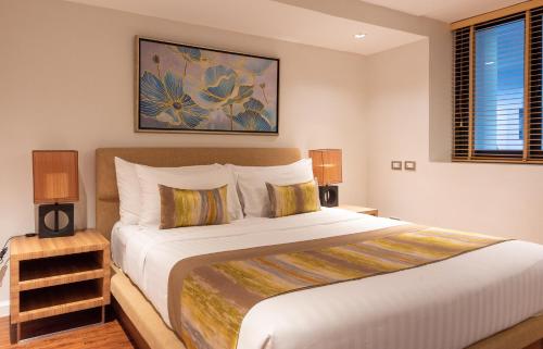 a bedroom with a large white bed with two lamps at Summit Windmill Golf Suite Hotel at Suvarnabhumi in Bangna