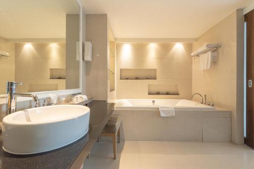a bathroom with a large tub and a white sink at Summit Windmill Golf Suite Hotel at Suvarnabhumi in Bangna