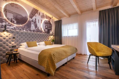 ein Schlafzimmer mit einem großen Bett und einem gelben Stuhl in der Unterkunft Hotel Zum Pinzger in Stumm