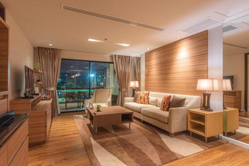 a living room with a couch and a tv at Summit Windmill Golf Suite Hotel at Suvarnabhumi in Bangna